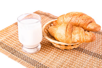 Fresh and tasty French croissants in a basket with glass of milk