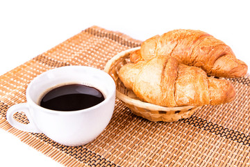 Fresh French croissants in a basket and cup of coffee