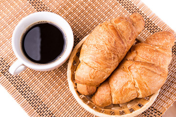 Fresh French croissants in a basket and cup of coffee