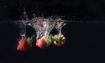 Trois fraises splash sur fond noir