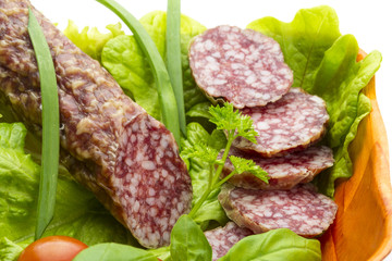 Ripe salami with salad, basil, onion and tomato
