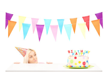 Birthday girl with a party hat looking at a birthday cake