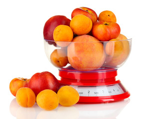 Ripe fruit in kitchen scales isolated on white