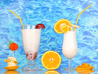 Delicious milk shake with fruit on table on blue sea background