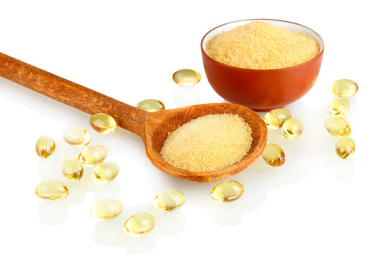 Gelatin in a bowl and wooden spoon on white background close-up