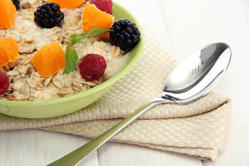 tasty oatmeal with berries and fruits, on white wooden table