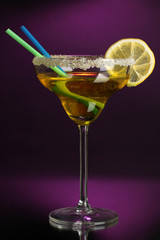 Yellow cocktail in glass on color background