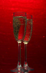Two glasses of champagne on bright background with lights