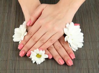 Obraz na płótnie Canvas Ręce kobiety z różowy manicure i kwiaty,