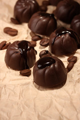 Chocolate candies and coffee beans, on beige paper background