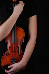 Violin in hands on black background