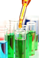 Laboratory pipette with drop of color liquid over glass test