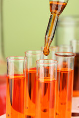 Laboratory pipette with drop of color liquid over glass test