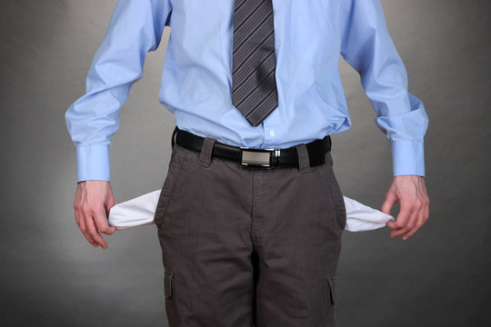 Business Man Showing His Empty Pockets, On Grey Background