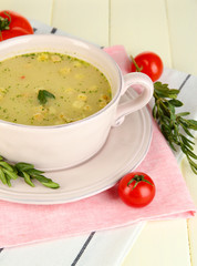 Nourishing soup in pink pan on wooden table close-up