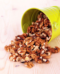 Overturned bucket with nuts on wooden background