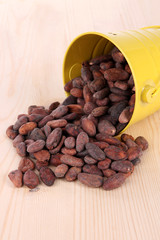 Overturned bucket with grains on wooden background