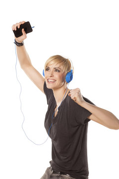 happy girl plays with headphones and music from her phone