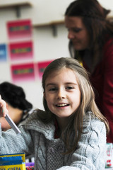 Happy little girl in school with her friends arround