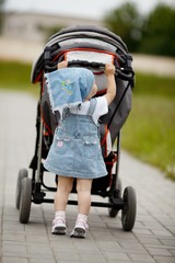 little funny girl with baby carriage