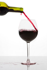 Ein Glas Rotwein eingiessen
