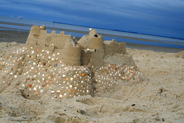 Sandburg am Strand mit Steinen u. Muscheln verziert . © Jörg Lantelme