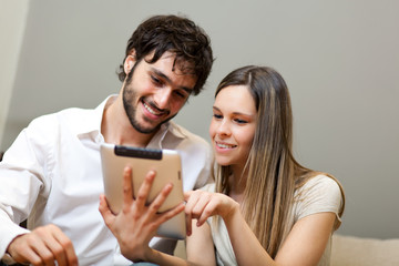 Couple sitting on sofa with electronic tablet