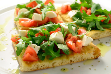 Focaccia with tomatoes, rocket, mozzarella and olives