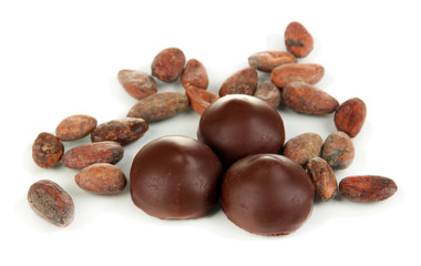 Chocolate candies and cocoa beans isolated on white