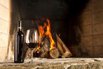 Copa de vino tino con fuego de chimenea de fondo.