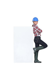Tradeswoman leaning against a blank sign