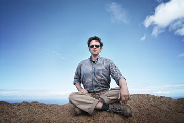 Naklejka na ściany i meble Man is sitting on a rock on top of the world, cotemplating