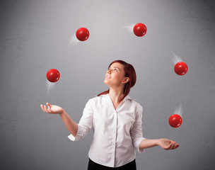 young girl standing and juggling with red balls