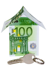 Silver key and a house build from 100 euro banknotes, isolated