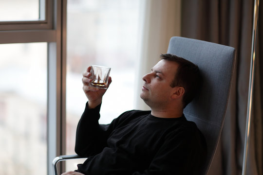 Man holds glass of whiskey