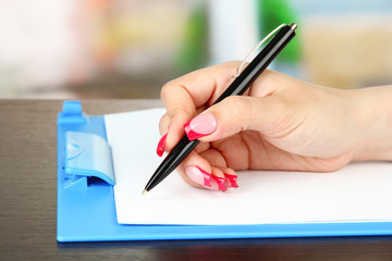 Female hand writing, on bright background