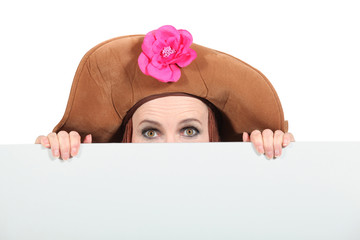Woman hiding wearing a big brown hat - obrazy, fototapety, plakaty