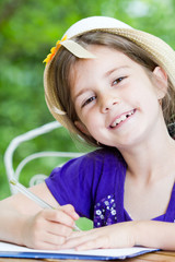 Little cchoolgirl working homework outside in beautiful nature