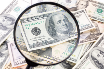 Hundred dollar banknote under magnifying glass