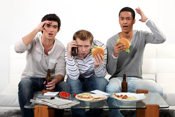 Three young eating burgers and drinking beer