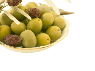Green olives in a white dish with leaves isolated on white