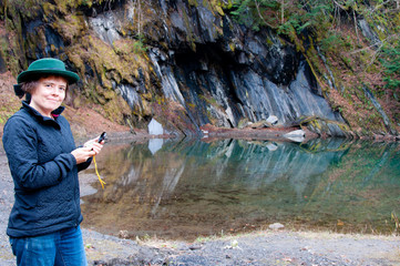 Woman checking compass by mountain pool