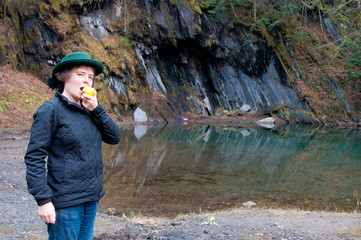 Woman eating apple by a mountain pool