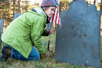 Woman placing a US flag in front of a soldier's gravestone