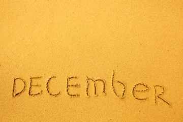 December - written in sand on beach texture.