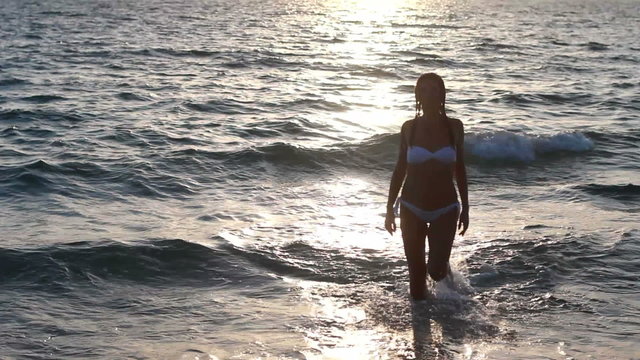 Silhouette of a girl in the water at sunset.
