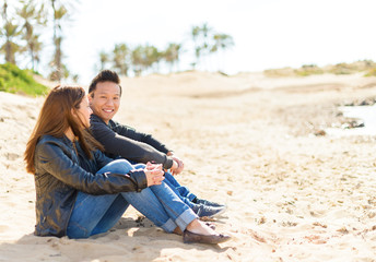 Fototapeta premium Young Couple Sitting On Beach