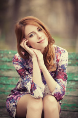 Style redhead girl sitting on the bench