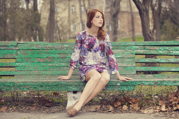 Style redhead girl sitting on the bench