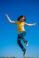 Obraz premium Girl jumping, running against blue sky
